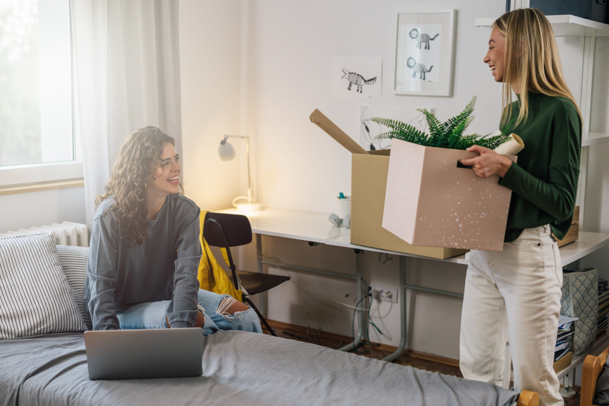 Two Young Women Are Moving Into A New Room In A Dormitory Two Young Women Are Moving Into A New Room In A Dormitory